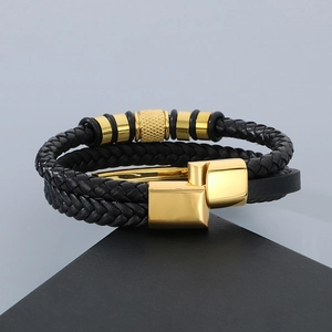 Close-up of black braided leather men's bracelet with polished gold magnetic clasp and beads
