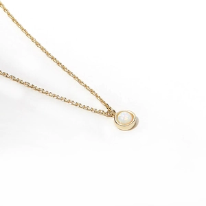 Macro shot of single round white opal pendant on a dainty gold plated silver chain