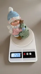Close-up of ceramic Christmas boy figurine weight measurement on a scale at 252.6g