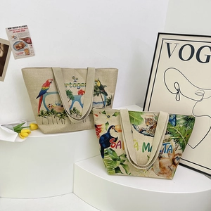 Detail view of linen tote bags with vibrant tropical prints and city name lettering