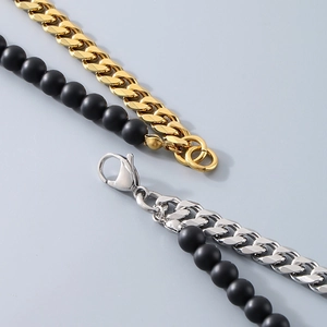Detailed macro view of gold and silver Cuban link chains with black matte beads and clasp
