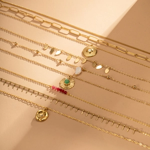 Detail of bohemian gold layered necklaces with sun pendant and green natural stones