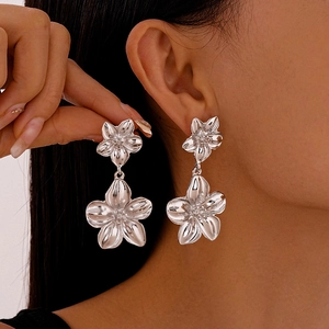 Polierte silberne Statement-Ohrringe mit doppeltem Metallic-Blumendesign am Modell