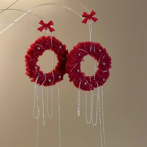 Detail of red plush hoop earrings with bow and hanging silver chain tassels