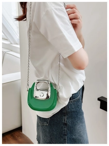 Mini green leather bag with silver metal handle and chain strap worn crossbody style