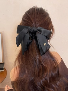 Close-up of black satin bow hair claw clip showing silk texture and metal detail