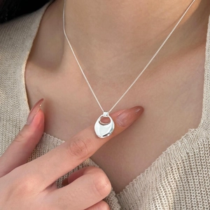 Detailed view of an irregular organic silver pendant necklace on a minimalist chain