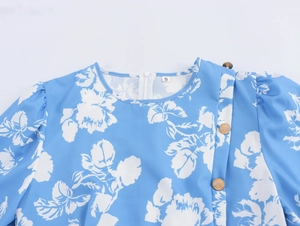 Detail eines blauen Blumenkleides mit Rundhals, Puffärmeln und goldenen Knöpfen