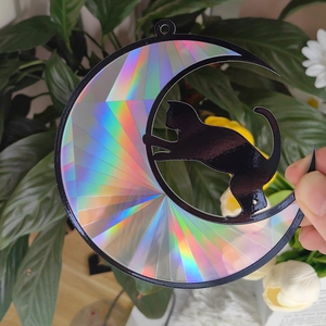 Detail of crescent moon cat suncatcher with iridescent surface reflecting rainbow light