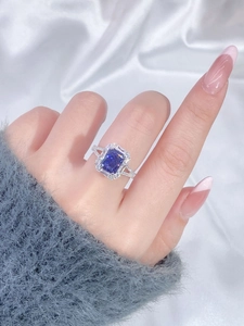 Macro shot of a silver ring with large blue square gemstone worn on a finger