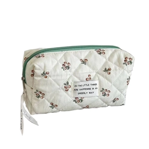 Quilted floral makeup bag in cream white with cherry print and green zipper detail