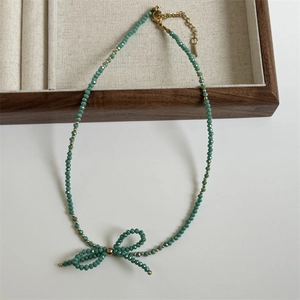 Detail of faceted teal beads handmade bow necklace with adjustable gold clasp