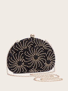 Detail of black shell clutch bag featuring gold beaded swirl patterns and gold chain strap