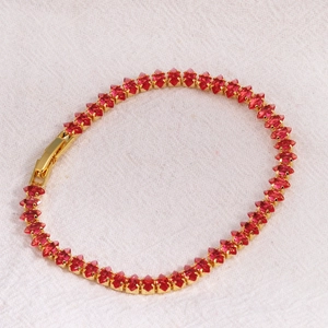 Detail of marquise-cut red crystals and gold-plated link chain on a knotted tennis bracelet