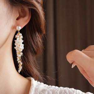 Close-up of floral tassel earrings with pearls and gold finish on female model