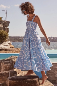 Detail of blue and white geometric print tiered maxi dress on a seaside rocky landscape