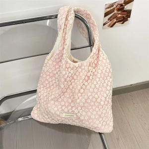 Detailed close-up of pink mesh tote bag with white floral daisy embroidery and brand label