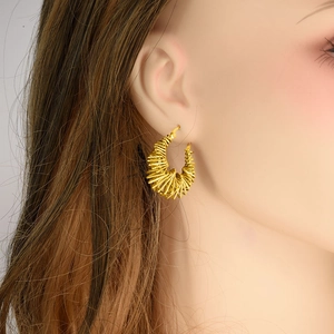Detailed side view of a model wearing the golden spiral woven hoop earrings