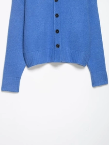 Close-up of blue knit cardigan featuring black buttons and ribbed hem texture