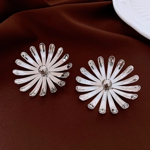 Detailed shot of silver daisy earrings with multi-layer petals on vintage red fabric