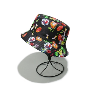 Detailed view of black bucket hat with vibrant tropical fruit and floral prints on stand