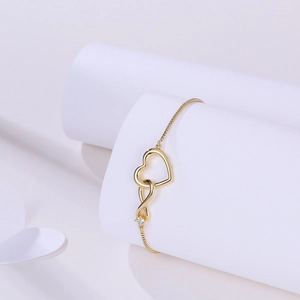 Detail of adjustable gold bracelet featuring interlocking heart and infinity zircon charms