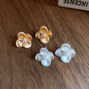 Detail view of matte flower earrings with sparkling cubic zirconia centers in gold and white