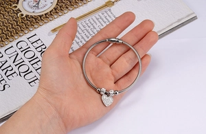 Close-up of silver snake chain bracelet with heart pendant and magnetic clasp on hand