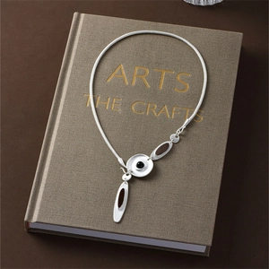 Detailed shot of irregular metallic disk necklace with dark stone inlay on book surface