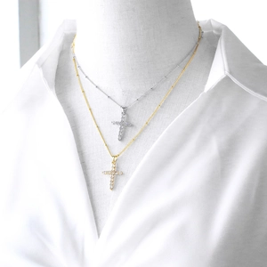 Elegant gold and silver cross necklaces with inlaid crystals on a white mannequin