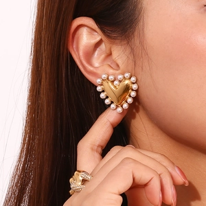 Detail of heart stud earring with 18K gold finish and white pearl border on model