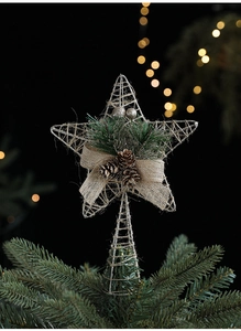 Close-up of silver wire Christmas star with pine cones and burlap bow on tree