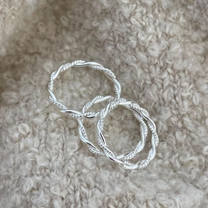 Close-up of three 925 sterling silver twisted rope rings on a beige knit fabric