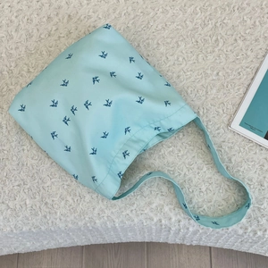 Close-up of light blue canvas tote bag featuring navy swallow print on soft white rug