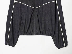 Détail de la veste gris foncé avec passepoil blanc et ourlet élastique sur le tissu