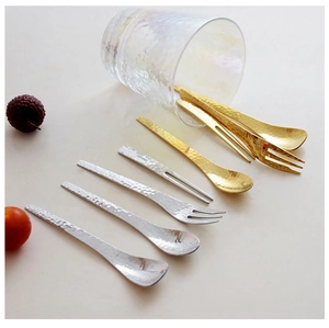 Artistic layout of hammered metal spoons and forks in gold and silver finishes