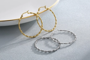 Detailed close-up of gold and silver bamboo texture hoop earrings on a ceramic plate