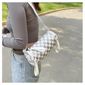 Detail view of checkerboard cylinder crossbody bag with wide shoulder strap on model