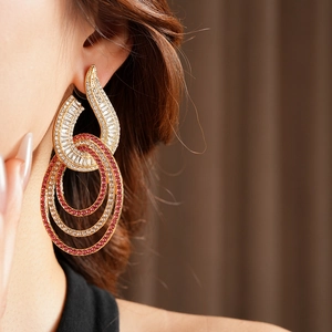 Detail view of gold layered hoop earrings with pink and white crystals on a model