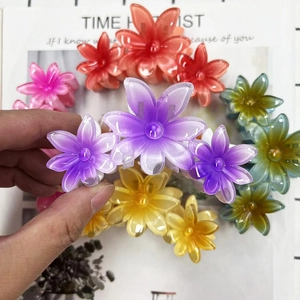 Detailed view of colorful translucent resin flower hair claws held by hand on a magazine