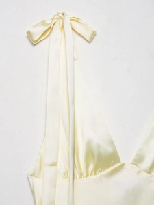 Detail of light yellow satin midi dress showing bow tie neckline and silky texture