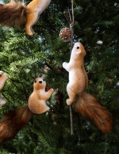 Close-up of lifelike squirrel Christmas ornaments on green pine tree branches