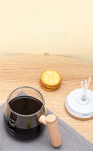 Detail of a glass automatic stirring mug with scale marks and a wooden handle
