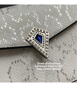 Macro view of white snakeskin texture bag with blue gemstone pentagonal metal buckle