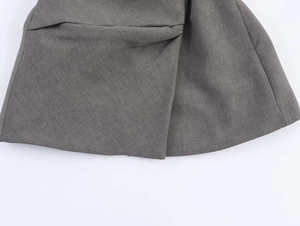 Gros plan sur la texture en sergé gris et l'ourlet superposé d'un pantalon de costume