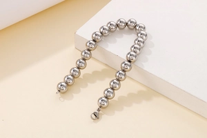 Detailed view of silver beaded stainless steel bracelet with lobster clasp on prop