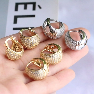 Vue macro de boucles d'oreilles huggies pavées de zircons avec motifs évidés fins