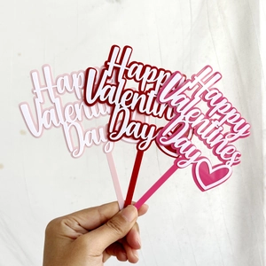 Three colorful acrylic Happy Valentine's Day cake toppers held in hand for display