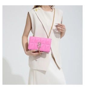 Detail of quilted bright pink shoulder bag with gold S-logo and stylish chain strap