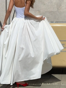 Detail of white pleated maxi skirt with light blue polka dot bodice and red heels